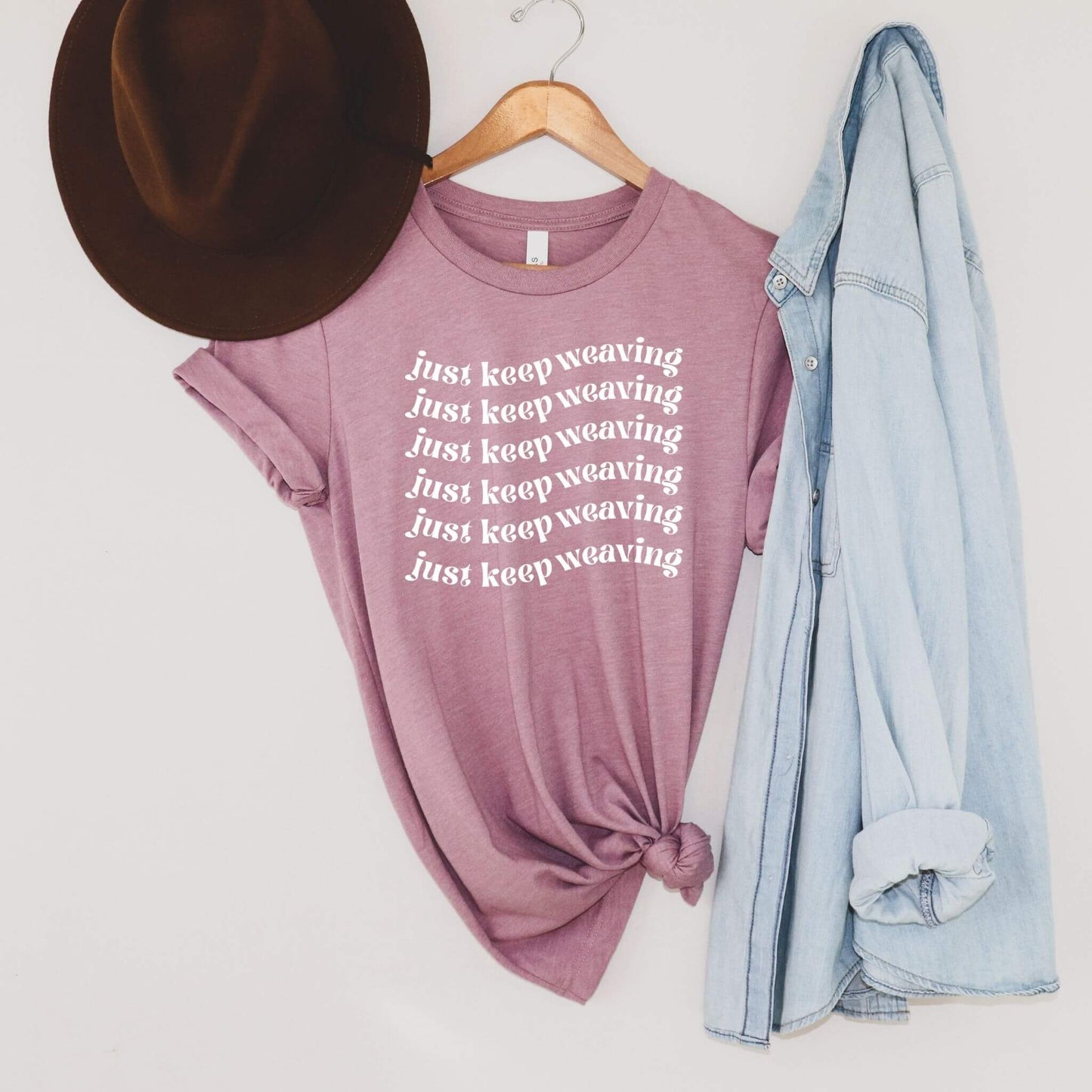 light purple t-shirt with words just keep weaving on it